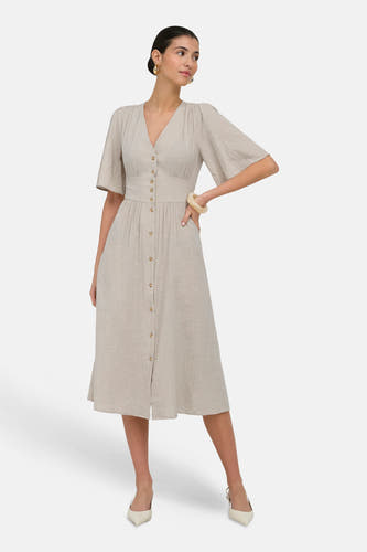 Robe beige à manches courtes de ONLY® aspect lin, avec col en V, fermeture boutonnée et taille cintrée, portée avec des boucles d'oreilles dorées et des escarpins slingback crème.