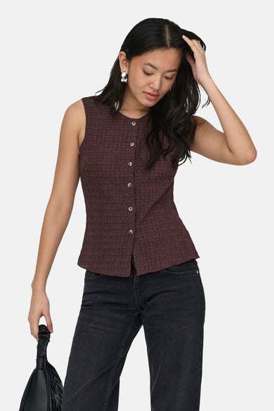 Gilet marron d'ONLY, avec fermeture à boutons sur le devant, combiné avec un sac à main noir et un jean foncé.