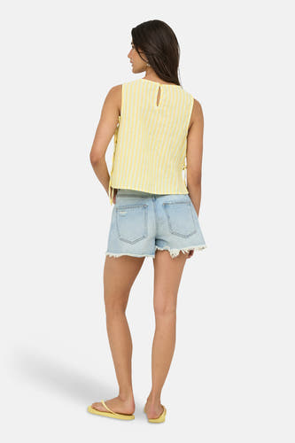 Chemisier sans manches à rayures jaunes de ONLY® avec détail en trou de serrure au dos, porté avec un short en jean et des tongs jaunes.