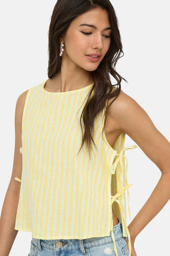 Chemisier sans manches jaune de ONLY® avec rayures verticales bleu clair et nœuds sur les côtés, porté avec un jean et des boucles d'oreilles en perles.