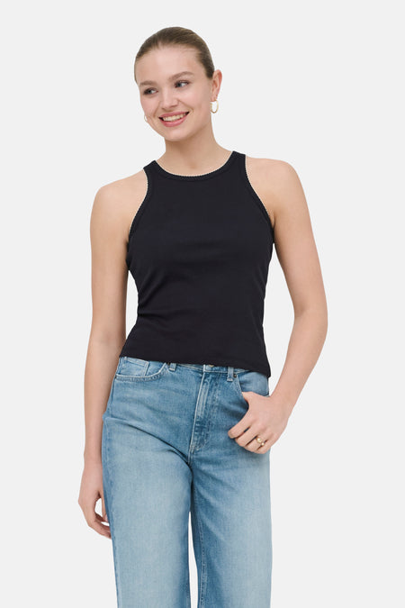 Débardeur noir de ONLY® avec bordure festonnée blanche au niveau de l'encolure et des emmanchures, porté par un mannequin avec un jean bleu clair.