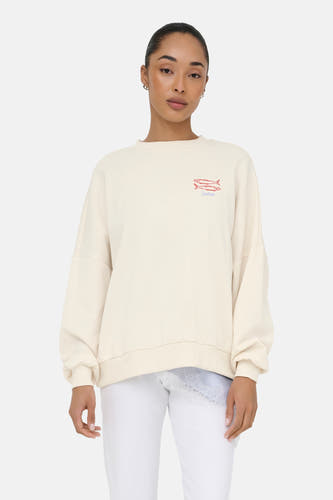 Pull beige à col rond de ONLY® avec motif de poisson brodé et 'Sardines', coupe oversize, porté sur un haut en dentelle bleu clair.