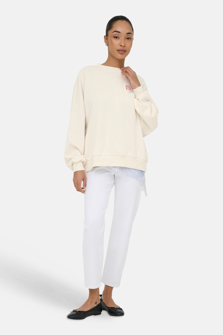 Beige sweater met ronde hals van ONLY® met geborduurd vismotief en 'Sardines', oversized pasvorm, gedragen over een lichtblauwe kanten top.