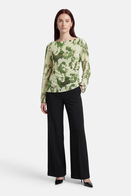 Groene T-shirt met lange mouwen van JDY, met een abstracte camouflageprint, gedragen met zwarte, uitlopende pantalon en pumps.