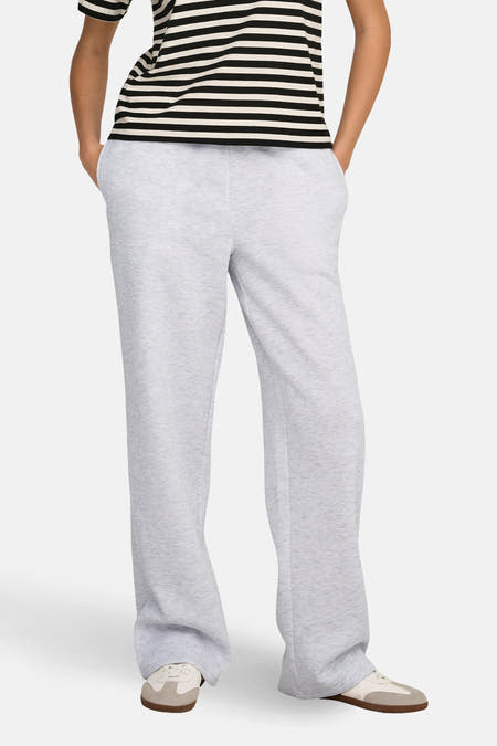 Grijze joggingbroek van ONLY, met wijde pijpen en steekzakken, gecombineerd met een gestreept shirt en crèmekleurige sneakers.