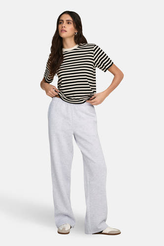 Grijze joggingbroek van ONLY, met wijde pijpen en gecombineerd met een gestreept T-shirt en sneakers.