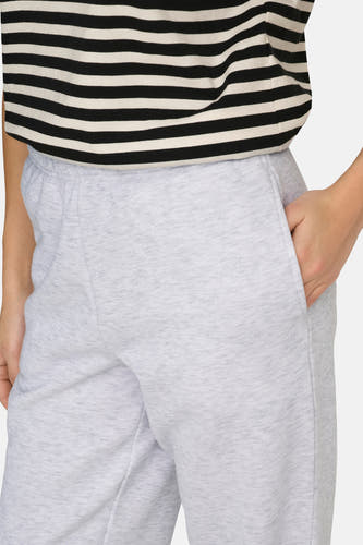 Pantalon de jogging gris d'ONLY, avec une main dans la poche et un t-shirt rayé.