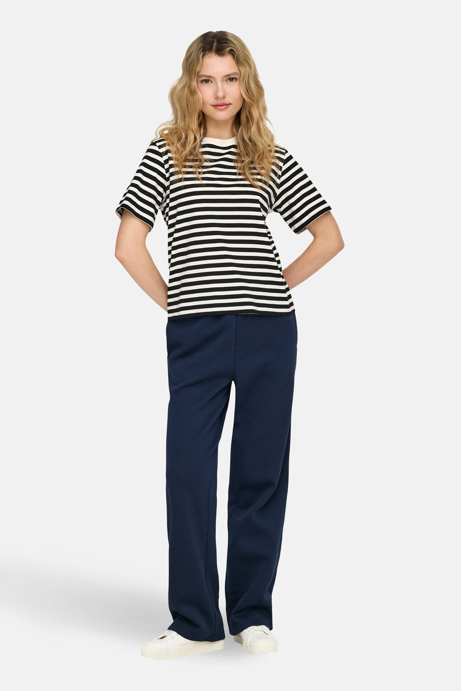 Pantalon de jogging bleu d'ONLY, porté avec un t-shirt rayé et des baskets blanches.