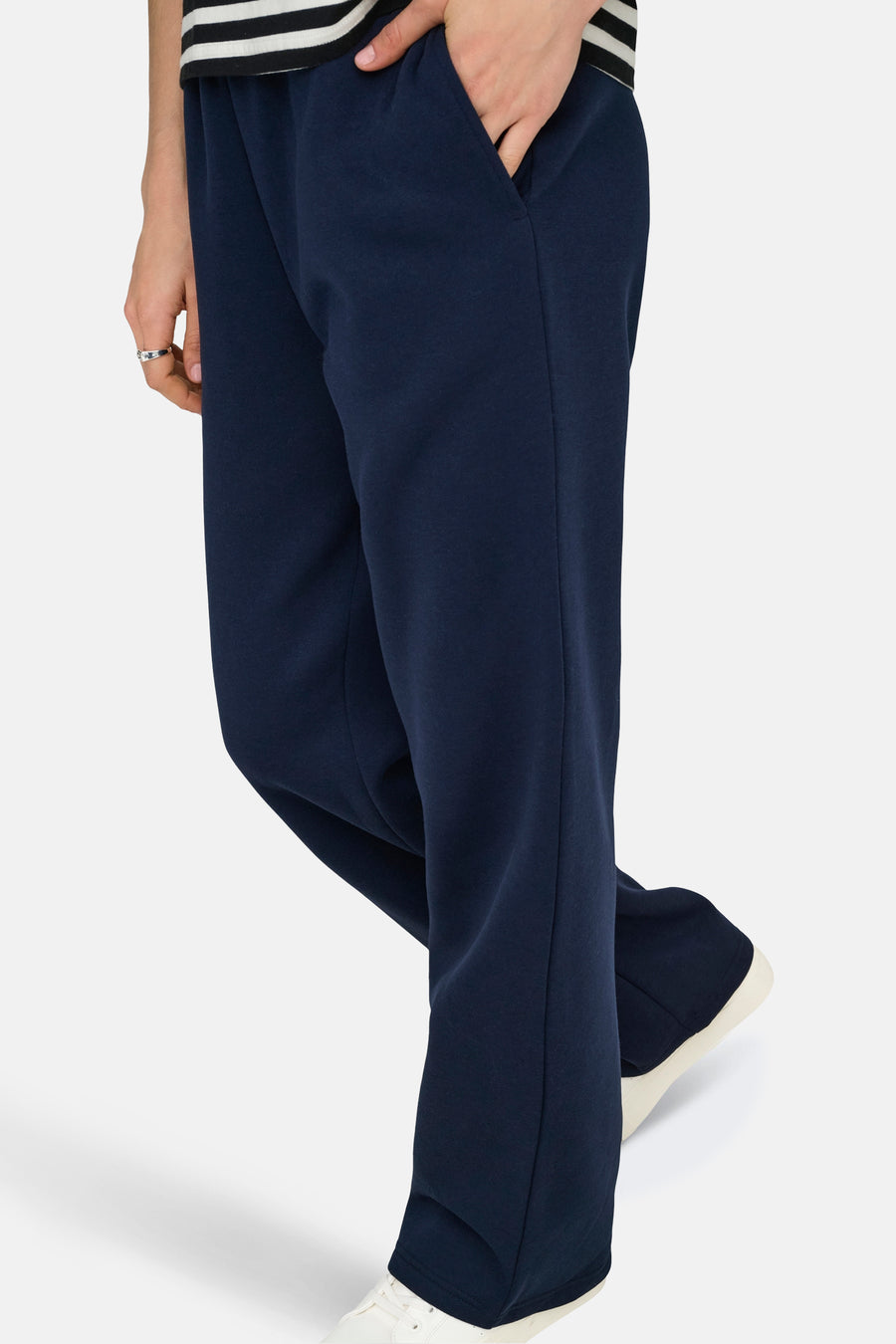 Pantalon de jogging bleu d'ONLY, avec poche latérale et porté avec un haut blanc à rayures et des baskets blanches