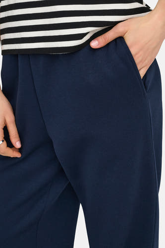 Pantalon de jogging bleu d'ONLY, avec une main dans la poche et un haut rayé.