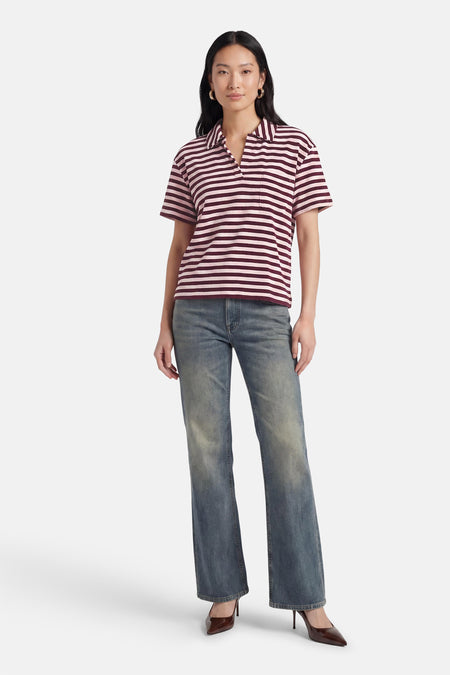 Polo à manches courtes à rayures roses et bordeaux de JDY, avec col, col en V et poche poitrine, porté avec un jean bleu.