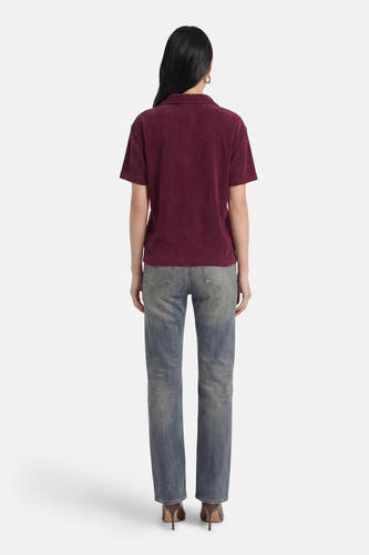 Polo violet à manches courtes de JDY, avec une texture douce, vue de dos, portée avec un jean et des talons marron.
