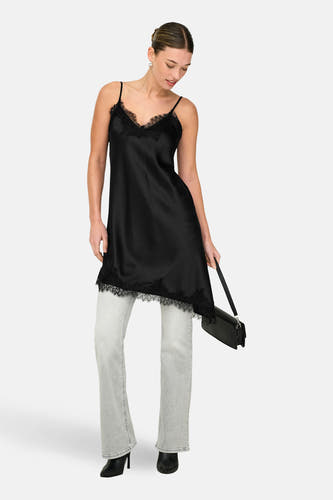 Robe noire sans manches ONLY, finie avec de la dentelle, combinée avec un jean gris et des talons noirs.