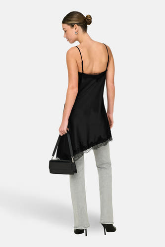 Robe noire sans manches ONLY, avec bordure en dentelle, associée à un jean gris, des talons noirs et un sac.