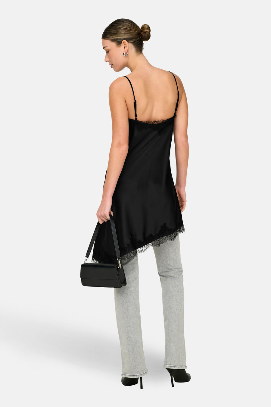 Robe noire sans manches ONLY, avec bordure en dentelle, associée à un jean gris, des talons noirs et un sac.