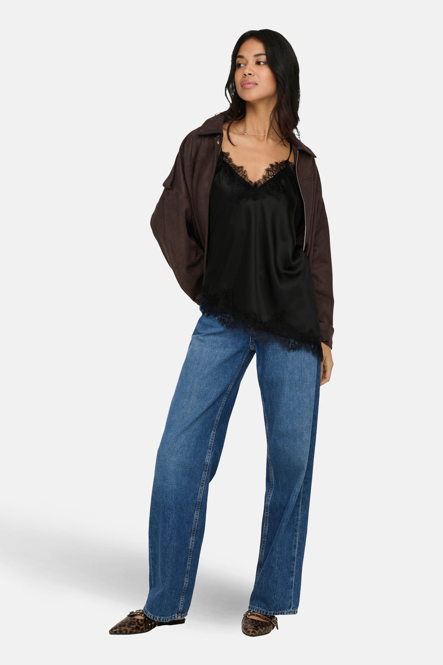 Chemisier noir sans manches de ONLY, avec détails en dentelle, combiné avec une veste marron et un jean bleu.