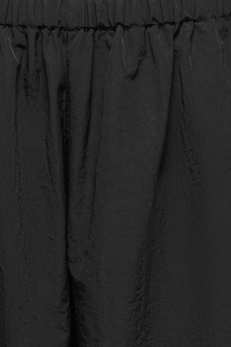 Pantalon noir ONLY, avec taille élastique et texture subtilement brillante.