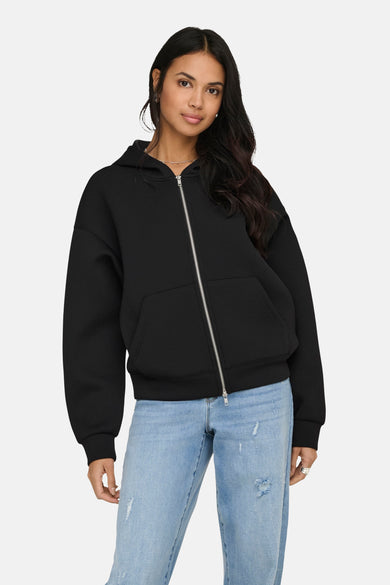 Pull noir à fermeture éclair de ONLY, avec capuche et poches, porté sur un jean bleu.