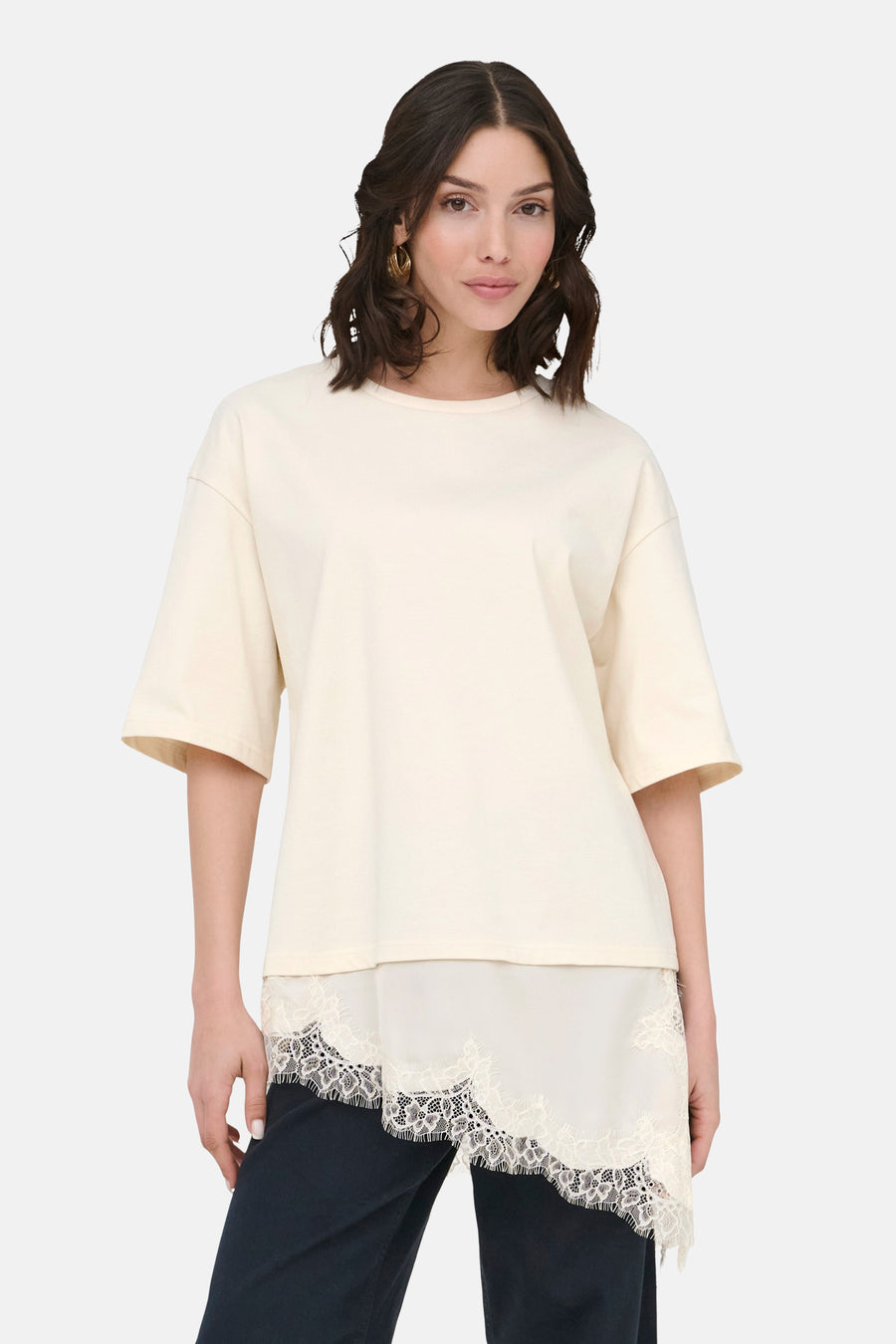 T-shirt beige à manches courtes de JDY, avec détails en dentelle sur le bas et porté avec un pantalon foncé.