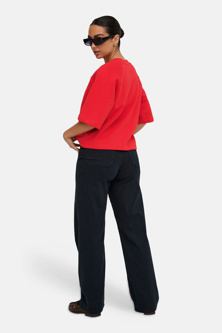 Rode ronde hals sweater van JDY, oversized fit, korte mouwen, model in zijprofiel met donkere broek en zonnebril