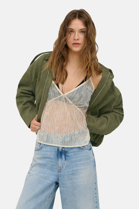 Chemisier sans manches en dentelle écru de ONLY®, porté avec une veste ouverte d'aspect suède vert et un jean clair.