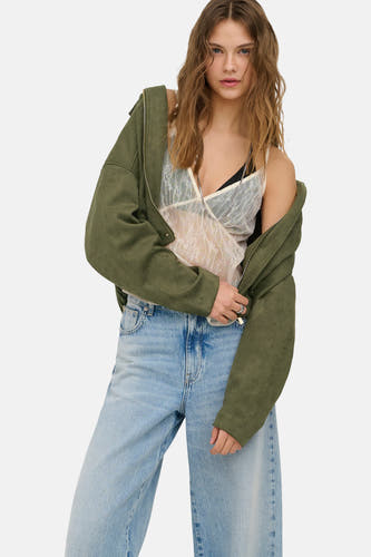 Chemisier en dentelle écru de ONLY®, avec col en V et porté sous une veste verte ouverte.