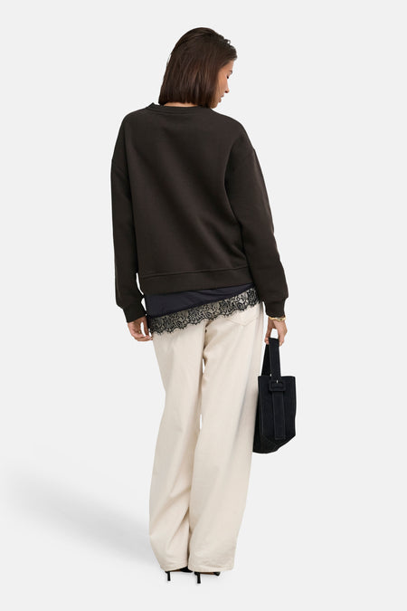 Donkere ronde hals sweater van JDY, achterzijde, met gebreide zoom en losse pasvorm, gedragen met witte broek en zwarte tas