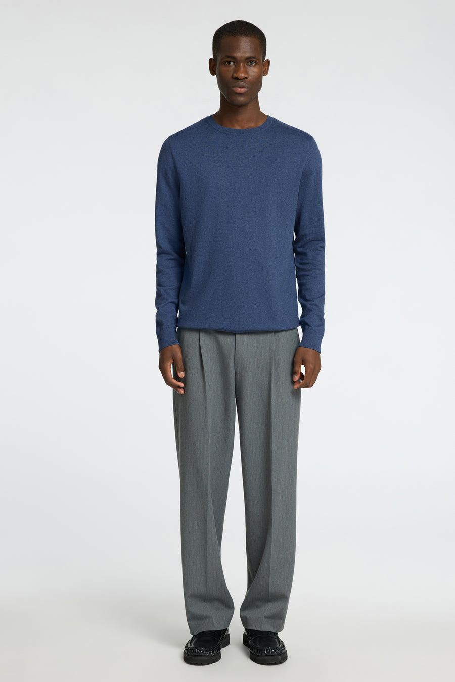 Pull bleu à col rond de SELECTED, combiné avec un pantalon gris et des chaussures noires.