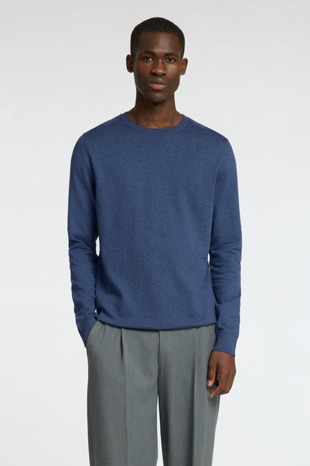 Pull bleu à col rond de SELECTED, combiné avec un pantalon gris, debout sur un fond blanc.