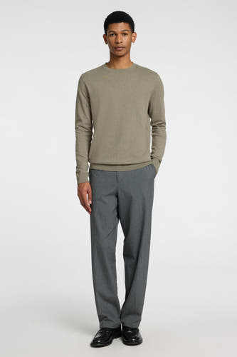 Pull vert à col rond de SELECTED, porté avec un pantalon gris et des chaussures noires.