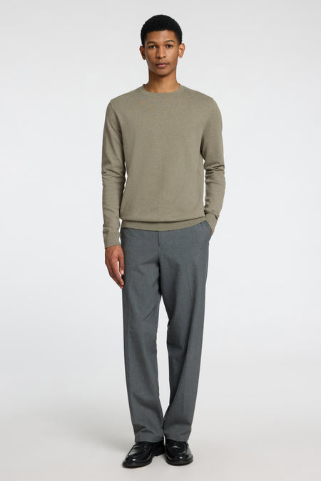 Pull vert à col rond de SELECTED, porté avec un pantalon gris et des chaussures noires.
