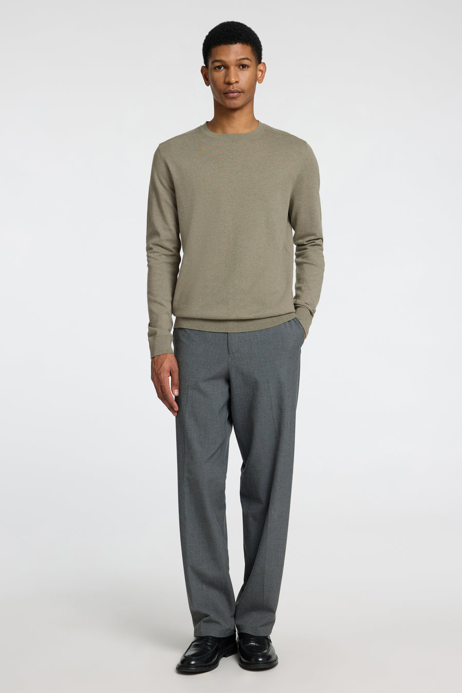 Pull vert à col rond de SELECTED, porté avec un pantalon gris et des chaussures noires.