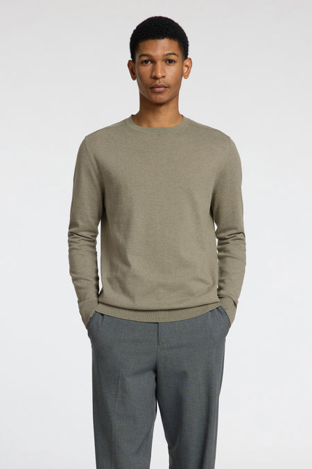 Pull vert avec col rond de SELECTED, combiné avec un pantalon gris, représenté debout sur un fond blanc.