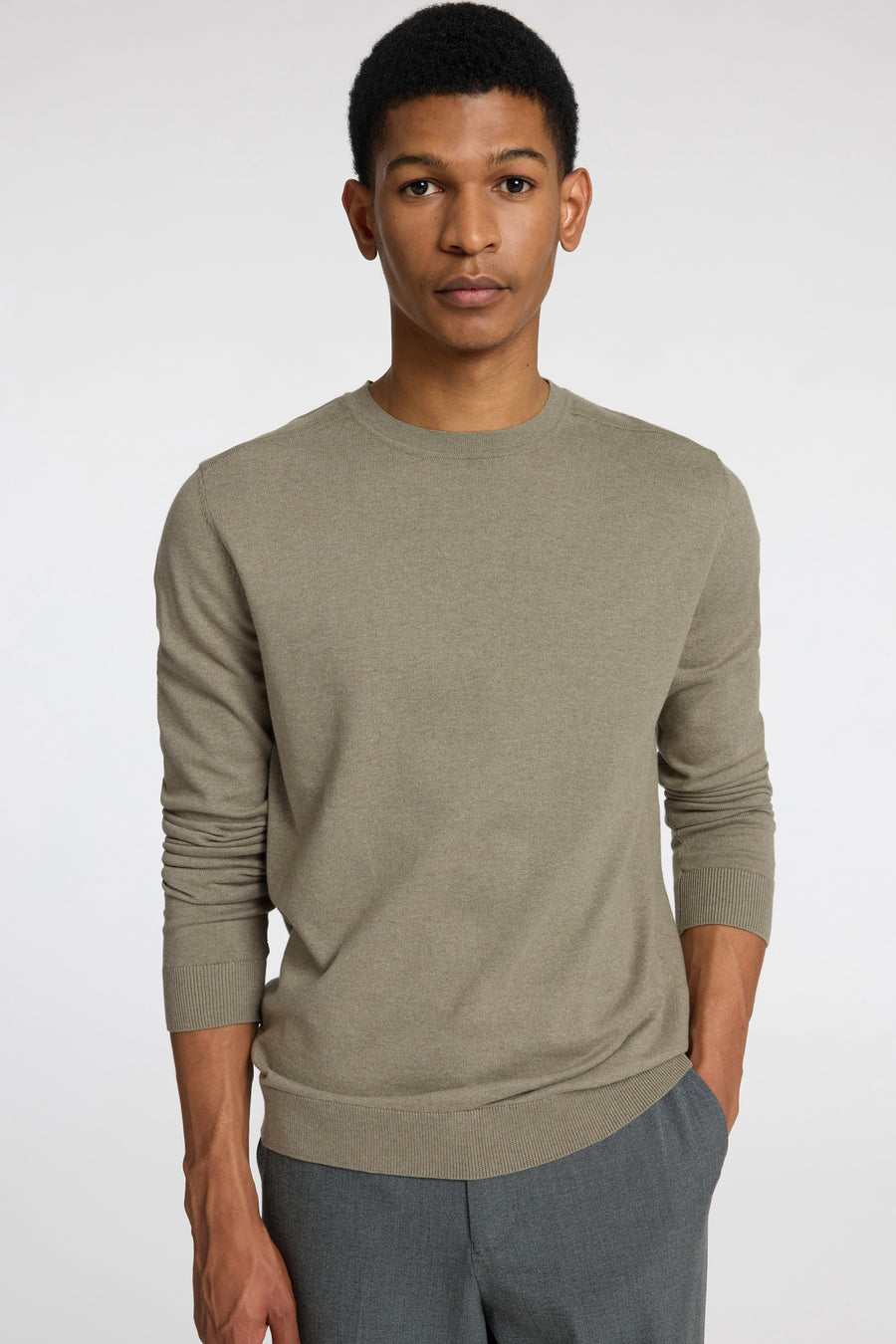 Pull vert avec col rond de SELECTED, porté avec un pantalon gris.