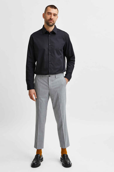 Chemise noire à manches longues de SELECTED, portée avec un pantalon gris et des loafers noirs avec des chaussettes marron.