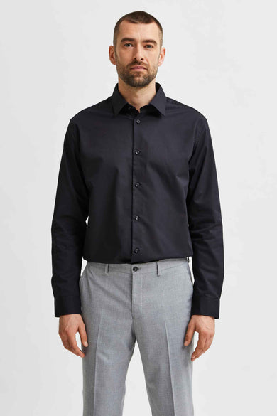Chemise noire à manches longues de SELECTED, portée avec un pantalon gris.