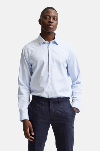 Chemise bleue à manches longues de SELECTED, lisse et portée avec un pantalon sombre à carreaux.