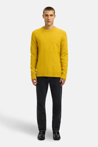 Gele trui met ronde hals van SELECTED, gedragen met een donkere jeans en zwarte leren instappers.
