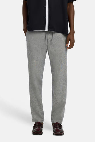 Pantalon bleu de SELECTED, avec un motif subtil et combiné avec un t-shirt blanc et une blouse noire.
