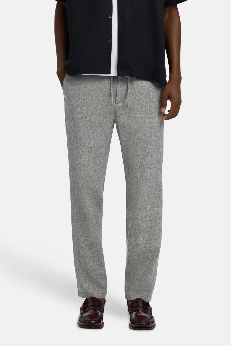Pantalon bleu de SELECTED, avec un motif subtil et combiné avec un t-shirt blanc et une blouse noire.