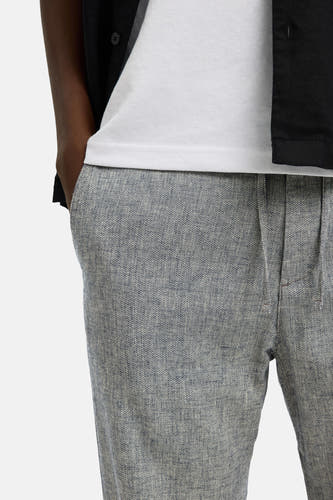Pantalon bleu de SELECTED, avec un motif chiné et une texture légère, porté avec un t-shirt blanc.