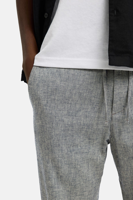 Pantalon bleu de SELECTED, avec un motif chiné et une texture légère, porté avec un t-shirt blanc.