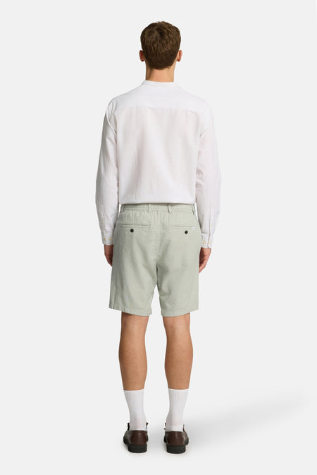 Short vert de SELECTED, avec des poches arrière et porté avec un chemisier blanc, des chaussettes et des chaussures.
