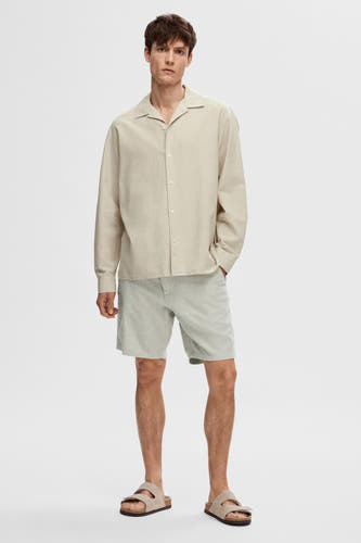 Groene short van SELECTED, gecombineerd met een linnen overhemd en sandalen.