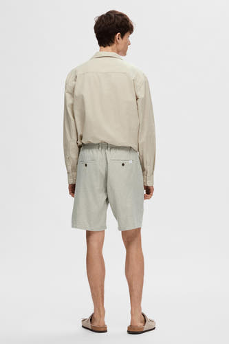 Groene short van SELECTED, gezien van achteren, met bruine knopen op de zakken en een elastische tailleband.