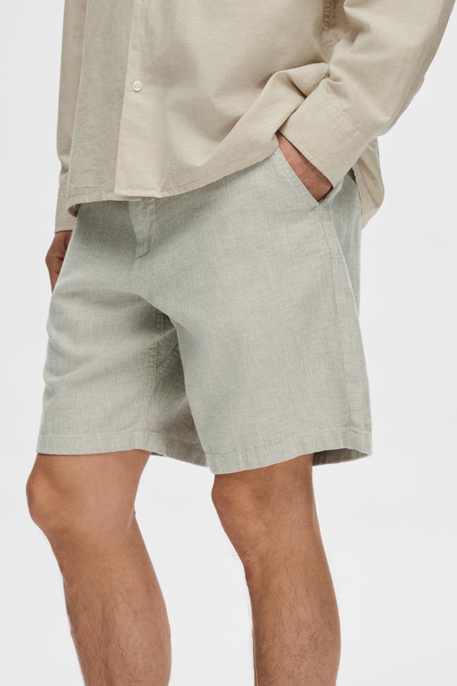 Short vert de SELECTED, avec une texture légère, des poches latérales et porté avec une chemise beige.