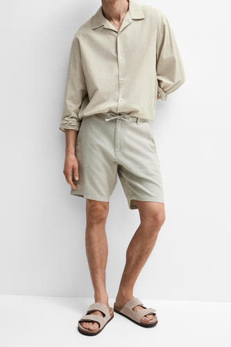 Short vert SELECTED, combiné avec une chemise de couleur claire et des sandales, debout sur un fond blanc.