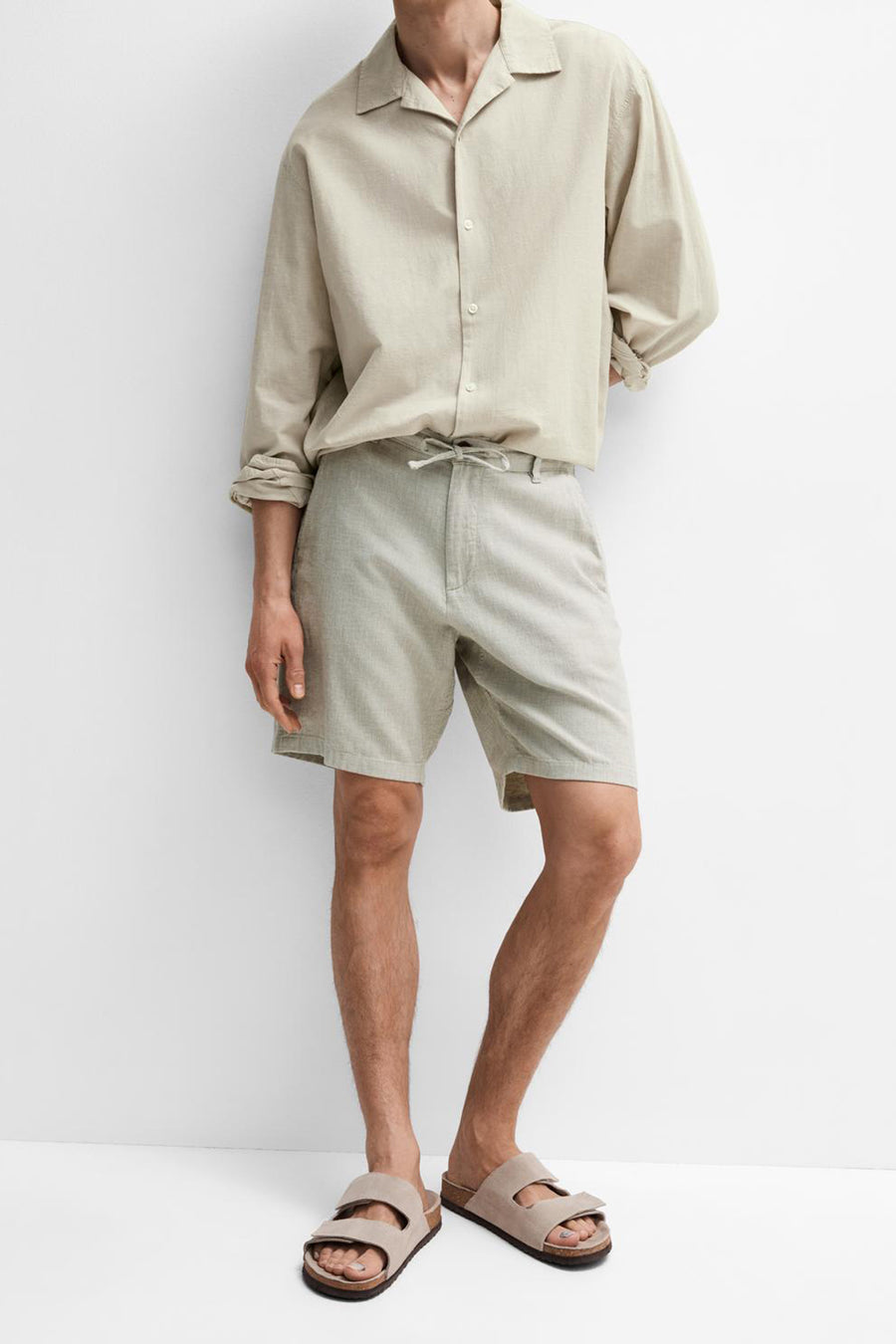 Short vert SELECTED, combiné avec une chemise de couleur claire et des sandales, debout sur un fond blanc.