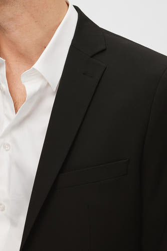 Blazer noir de SELECTED, avec revers et poche poitrine, porté sur une chemise blanche.