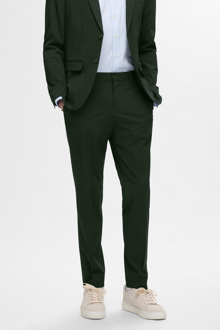 Pantalon de costume vert de SELECTED, porté avec un blazer coordonné, des chaussettes blanches et des baskets en suède, en vue latérale.